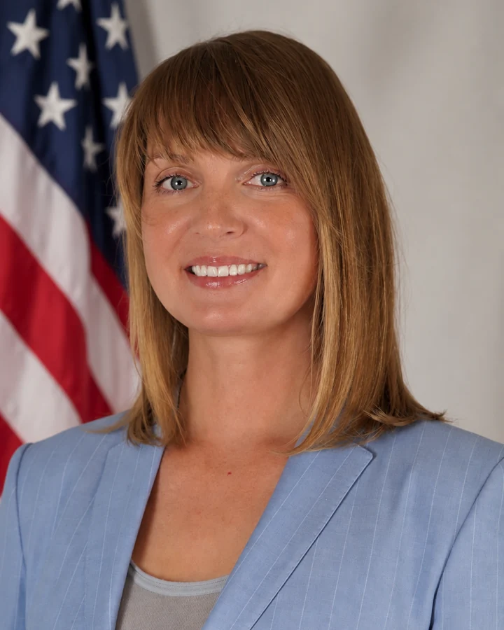 Campaign portrait of Alexandra Platonova wearing a light blue jacket, with an American flag behind her